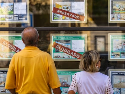 Dos personas miran los anuncios de una inmobiliaria en Madrid.