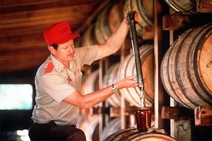 Un trabajador de la destilería estadounidense llena directamente del barril una botella de <i>whisky.</i>