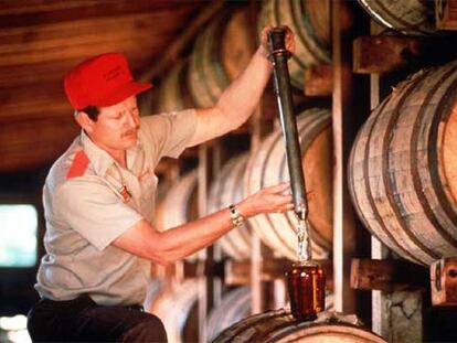 Un trabajador de la destilería estadounidense llena directamente del barril una botella de <i>whisky.</i>