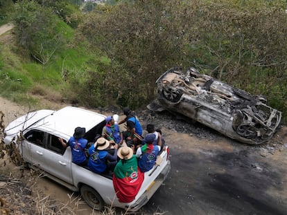 Miembros de la Guardia Indígena pasan junto a un vehículo que incendiado por rebeldes del Estado Mayor Central (EMC), en Toribio, Colombia, el 19 de marzo.