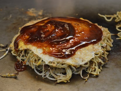 Un 'okonomiyaki' listo a comer con salsa por encima.