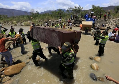 Cientos de colombianos, con ayuda de miembros de la Policía colombiana, cargan sus pertenencias por el río Táchira desde Venezuela hacia el sector La Parada (Colombia).