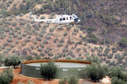 Un helicóptero carga agua de un depósito para intentar apagar el fuego localizado en el Parque Natural de las Sierras de Cazorla, Segura y Las Villas, en Jaén.