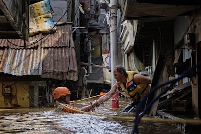 Un miembro de los equipos de rescate ayuda a un hombre a salir de su casa tras las inundaciones que han asolado Yakarta (Indonesia), el día 2 de enero.