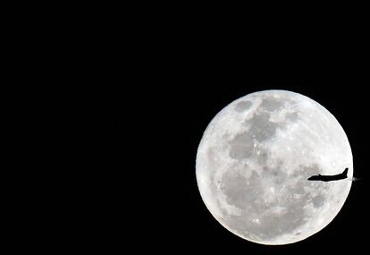 Un avión vuela frente a una luna llena en Sydney (Australia).