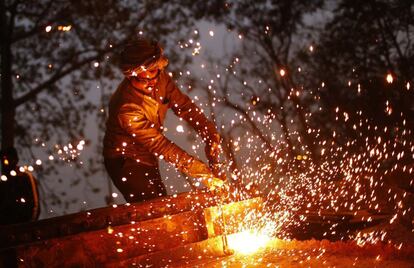 Un trabajador suelda una máquina de hierro en una obra de construcción en un paso elevado en Nueva Delhi (India). 