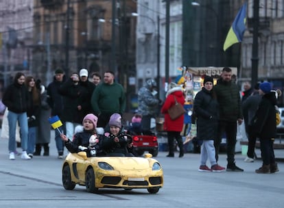 Dos niños, uno de ellos con una bandera ucrania, se divierten conduciendo un coche de juguete por el centro de Lviv, el 14 de marzo.