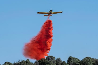 Cuatro hidroaviones del Ministerio de Medio Ambiente, junto con ocho helicópteros del Gobierno regional madrileño, intentan controlar las llamas. En la imagen, una avioneta suelta su carga sobre el Cerro de los Palos de Toledo, este viernes.