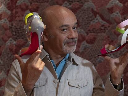 El diseñador Christian Louboutin, con dos de los zapatos que se venden en su nueva tienda de Barcelona. 