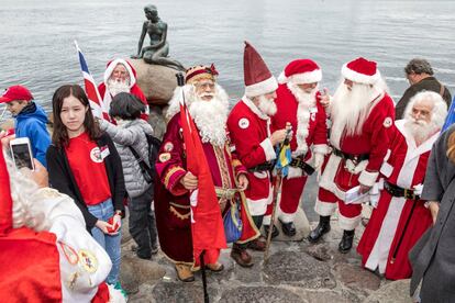 Personas vestidas de Santa Claus junto a la sirenita, emblema de la capital danesa, durante el Congreso Anual de Santa Claus.