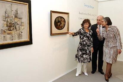 Carmen Calvo, Juan Manuel Urgoiti y Ana Martínez de Aguilar (de izquierda a derecha), durante la presentación de <i>Botella y fruta</i>s (1911), a la izquierda, y <i>Naipes y dados </i><b>(1914), de Braque.</b>