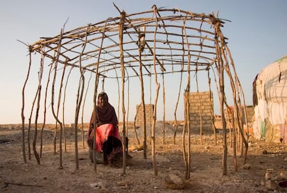 Una mujer se <i>cobija</i> bajo una construcción rudimentaria elaborada con frágiles palos de madera en Somalia, uno de los países del cuerno de África.