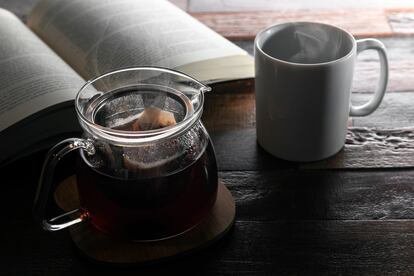 Una tetera junto a una taza sobre una mesa de madera.