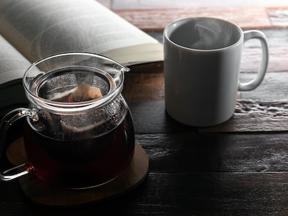 Una tetera junto a una taza sobre una mesa de madera.