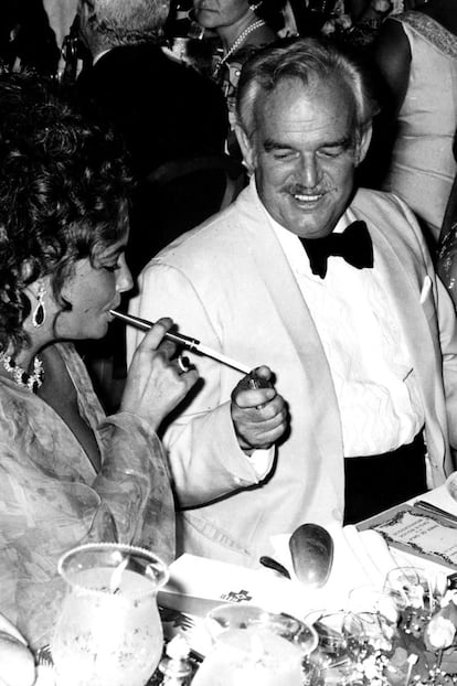 Liz Taylor era sinónimo de <i>glamour</i>. En esta foto, junto al príncipe Raniero de Mónaco, fumando en una cena en los años setenta.