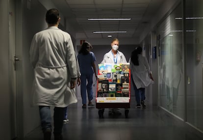 Marisa Guerra, una de las responsables de la biblioteca para pacientes del hospital Clínico, empuja el carrito cargado de libros.