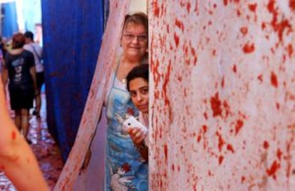 Unas vecinas se asoman a la puerta de su casa tras la Tomatina 2014.