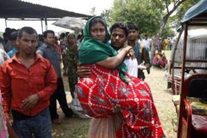 Un hombre lleva en brazos a su mujer, ambos supervivientes del derrumbe ocurrido el 24 abril, en Daca, Bangladés.