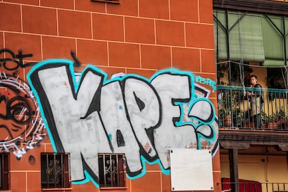 Una mujer mira desde la terraza de su vivienda en la plaza de Agustín de Lara.