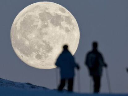 Três praticantes de esqui de montanha contemplam a lua cheia em Weissfluhjoch, em Arosa (Suíça), um dia antes do solstício de inverno.