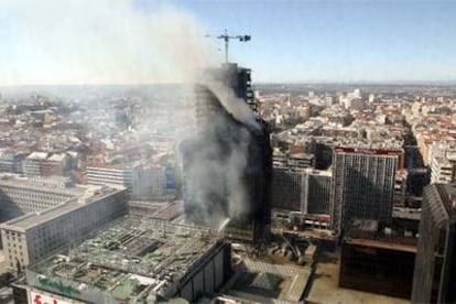 Vista del edificio siniestrado ayer por la mañana, envuelto en humo.