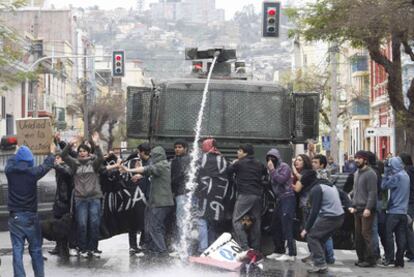 Un vehículo policial dispara agua a presión a un grupo de manifestantes en Santiago.