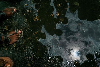 Varias personas miran el eclipse solar reflejado en un charco del suelo, en la ciudad de Dar es Salaam (Tanzania).