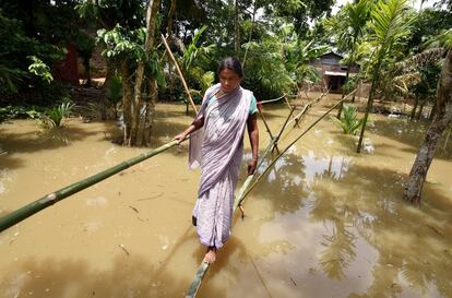 Una aldeana utiliza un puente improvisado de bambú para cruzar una zona inundada en el distrito de Nagaon, en el estado nororiental de Assam, India.