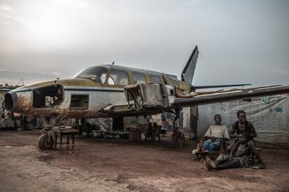 La familia Bercaille junto a la avioneta que sirve de refugio en el campo de desplazados del aeropuerto de M'Poko, en Bangui (República Centroafricana). Más de 28.000 personas llevan tres años viviendo en condiciones de extrema vulnerabilidad tras haber huido de sus viviendas por la escalada de violencia que se inició el 5 de diciembre de 2013.