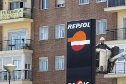 Un operario trabaja en un panel de Repsol en una gasolinera de Madrid.
