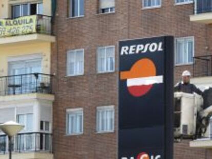 Un operario trabaja en un panel de Repsol en una gasolinera de Madrid. 