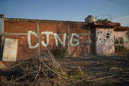 The initials of the Jalisco New Generation Cartel in a wall riddled with bullet holes in Michoacán.