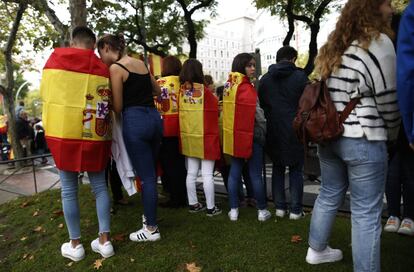 Un grupo de jóvenes con la bandera nacional esperan el comienzo de la tradicional parada militar en el centro de Madrid.