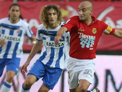 El delantero del Gimnátic, Antonio Pinilla controla el balón ante el defensa argentino del Deportivo Fabrizio Coloccini.
