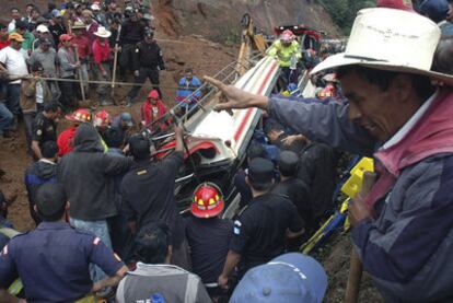 Equipos de rescate y voluntarios guatemaltecos intentan rescatar a los ocupantes de un autobús enterrado por un alud de barro cerca de Tecpan.