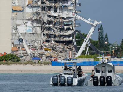 Botes de la policía de Miami vigilan a lo lejos los restos del edificio colapsado.