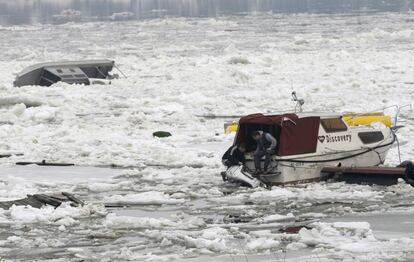 Dos hombres reparan su embarcación dañada por el hielo.