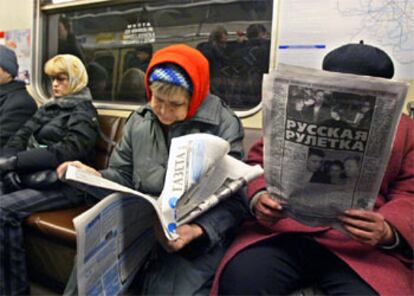 Varios ciudadanos rusos leen los resultados electorales en el periódico esta mañana en el metro de Moscú.