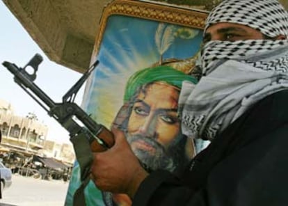 Un miliciano chií sujeta su arma junto a un retrato del imán Alí, en una calle de Bagdad.