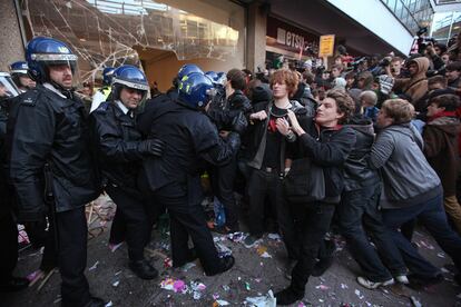 Policías antidisturbios y manifestantes se enfrentan a las puertas de la sede del Partido Conservador.