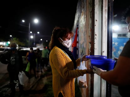 En plena pandemia de covid-19, una mujer entrega una ración de guiso en un comedor social para ayudar a la gente de bajos recursos, en Buenos Aires, Argentina, el  23 de abril de 2020.