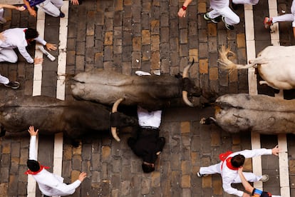 Un mozo permanece tumbado en el suelo al paso de los toros de José Escolar por la calle Estafeta. 