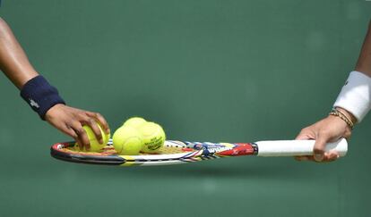 Una ni&ntilde;a coloca varias pelotas de tenis en la raqueta de Kei Nishikori de Jap&oacute;n durante el partido de tenis individual contra Mikhail Kukushkin de Kazajst&aacute;n.