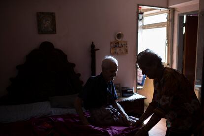 Martina Veranea ayuda a su esposo Donato Hernández de 92 años en su pequeño departamento de Caracas.