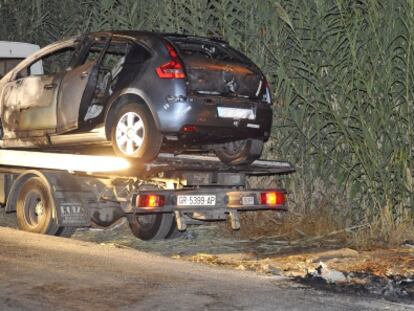 Un policía investiga el lugar en el que apareció el vehículo calcinado.