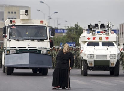 Una mujer de la etnia musulmana uigur se detiene delante de un vehículo militar blindado en Urumqi para pedir información sobre los cientos de detenidos
