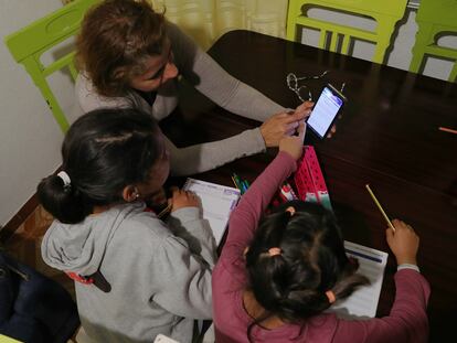 Flor Pérez Carrillo ayuda a hacer los deberes a sus dos hijas de 9 y 6 años, en su casa de Madrid, con la única ayuda de un móvil, ya que no han llegado las tabletas y portátiles prometidos por el ministerio y las comunidades.