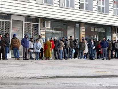 Varias personas forman una larga cola ante una oficina del INEM. 