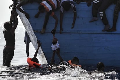 Varios migrantes intentan subir a bordo a un bebé mientras esperan a los miembros de la ONG Proactiva Open Arms, el 4 de octubre. 1.800 personas han sido rescatadas cerca de la costa líbia.