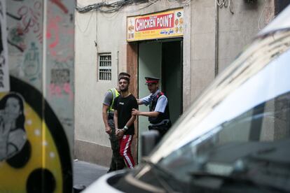 Agentes de los Mossos d'Esquadra custodian a un detenido durante el registro del restaurante Chicken Point en la calle Sant Marti del Raval, Barcelona, el 19 de junio de 2019. Los Mossos d'Esquadra, la Guardia Urbana y el Cuerpo Nacional de Policía realizaron una macrooperación conjunta contra el tráfico de drogas en el barrio del Raval.